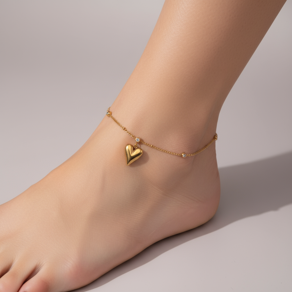 Brățară de picior modernă și strălucitoare, accesoriu feminin din lant cu 3 pietricele si un pandantiv cu inima aurie plina, la glezna unei femei.