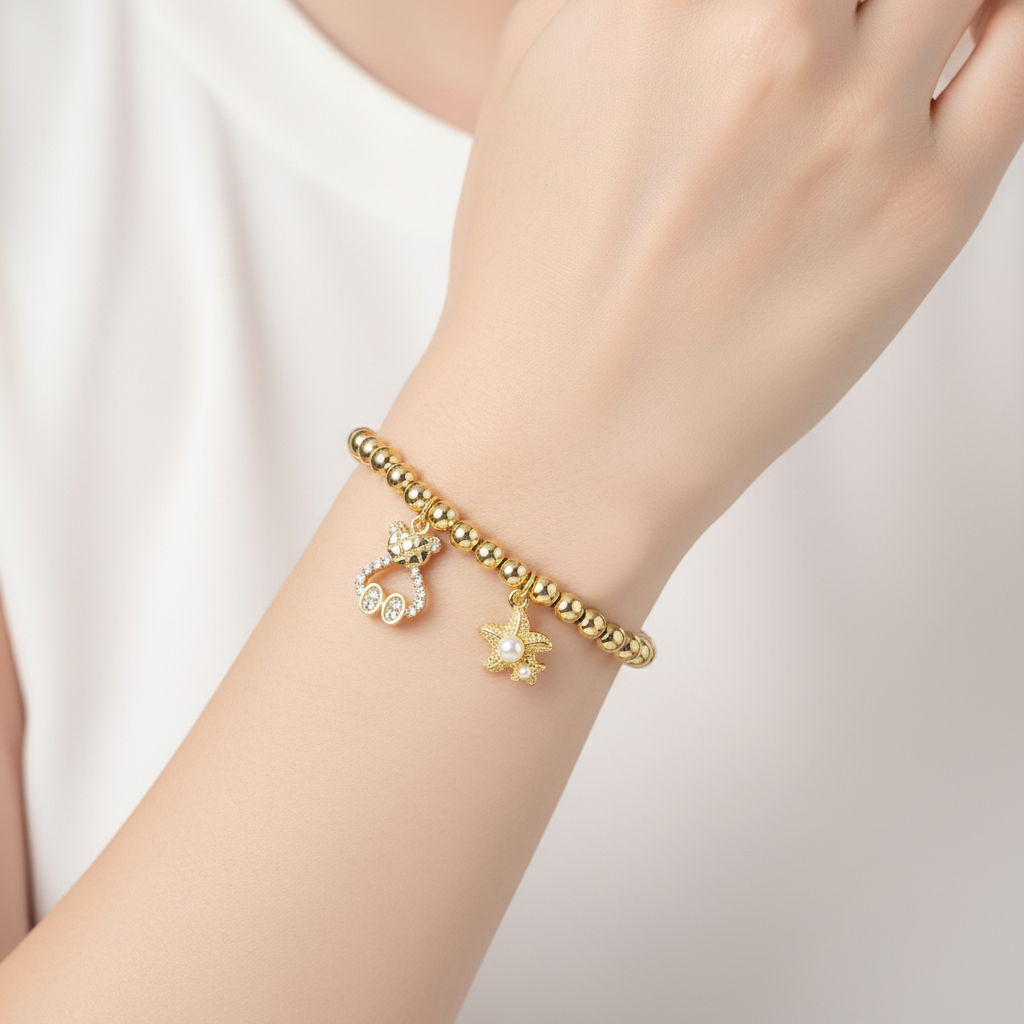 Brățară pe elastic cu bile aurii și charm cu ursulet si stea de mare